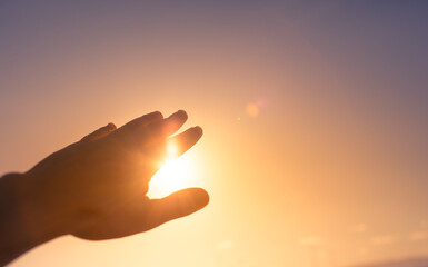 Fototapeta na wymiar hand reaching out to sky touching the warm sunshine. Happiness in nature, spiritual healing concept. 