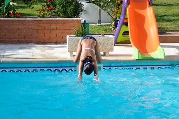 niña se tira de cabeza a la piscina
