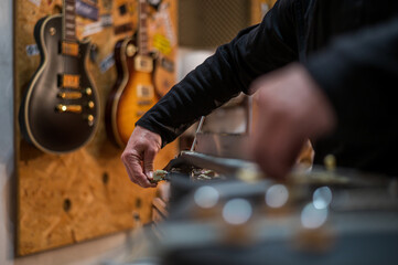 Guitar in repair service shop with a hands of a guitar luthier which fixes it