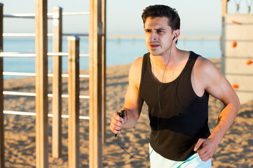Concentrated athletic man running on seashore in daytime
