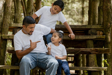 Young father with his children having a fun time in the park-Hispanic father playing with his...