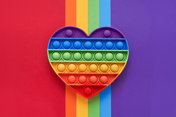 Colorful trendy Pop it fidgets toy on a rainbow background. Toy anti-stress, simple dimple. LGBT concept. Top view - obrazy, fototapety, plakaty