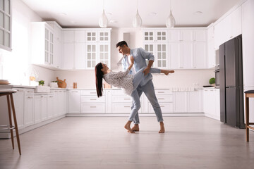 Happy couple dancing barefoot in kitchen. Floor heating system