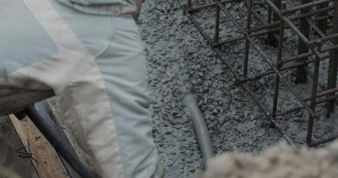 Worker is getting rid of excess concrete with a tube, construction site, 4k