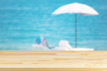 wood table top on blur beach umbrella on the sea background