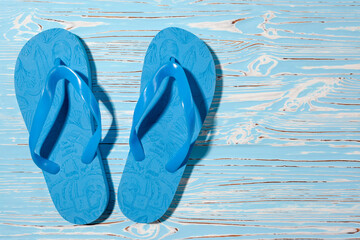 Blue rubber beach flip flops on a blue wooden background, place for text