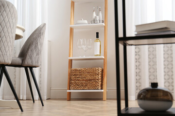 Stylish ladder shelf with kitchenware in dining room
