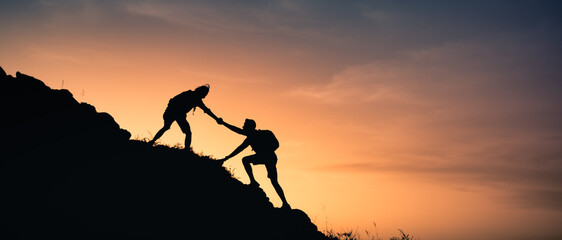 Hikers climbing a mountain giving a helping hand up the cliff. Teamwork, and never giving up...