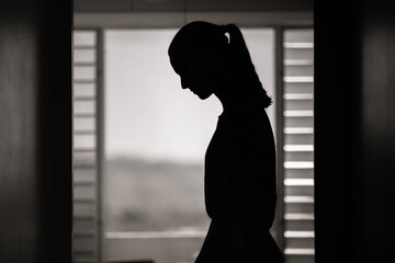 Sad depressed young woman indoors silhouette