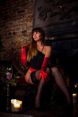 Obraz na płótnie Canvas nude woman in silk gloves is sitting next to the fireplace