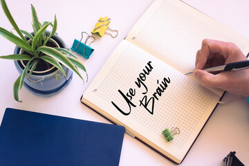 Fototapeta premium Closeup of a personal agenda setting an important date writing with pen. The words Use your Brain written on a white notebook to remind you an important appointment.
