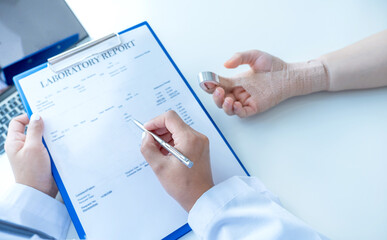 Doctors hand holding pen and report health examination results, recommend medication to patients in arm accident