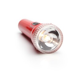 Red torch type flashlight with lighted bulb. Isolated on white with natural shadow.