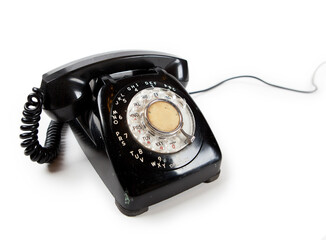 Old Late 60s - 70s style black telephone with rotary dial. Isolated on white. Cable extending in to...