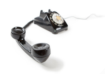 Old Late 60s - 70s style black telephone with rotary dial. Isolated on white. Hand set off the hook...