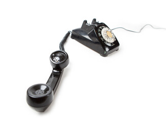 Old Late 60s - 70s style black telephone with rotary dial. Isolated on white. Hand set off the hook...