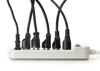 Many electrical cords connected to a white power strip or extension block. Isolated on white.