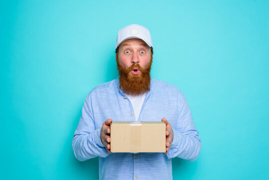 Courier with carton box in hand is surprised about something