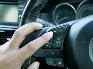 closeup of male hand pushing button on the steering wheel in a modern car.