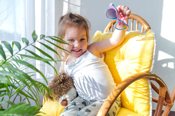 Defocus. Girl todler sits in a rocking chair in the sun. Candid people concept.