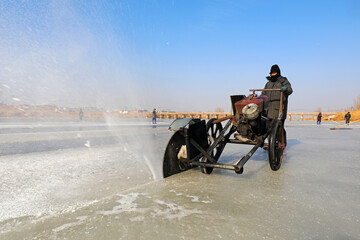 Farmers use electric saws to cut river ice in the wild.