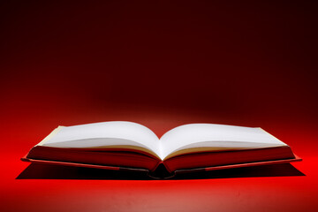 A book that looks like a Bible open in dark and red color background with very bright golden light on the page. Spiritual Life concept.