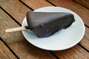 A slice of frozen key lime pie covered with chocolate on a stick