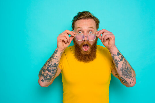Man with yellow t-shirt and beard is shocked about something
