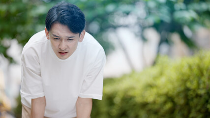 屋外で暑がる若い男性