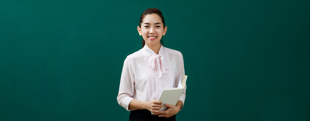 Portrait shot of Asian beautiful female teacher lecturer standing holding book in hands look at...
