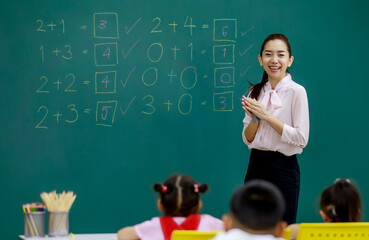Portrait shot of Asian beautiful female mathematic teacher standing smiling cheer up while little...