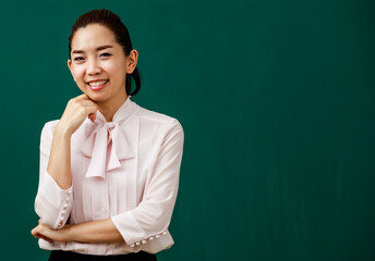Portrait closeup shot of Asian young female beautiful school teacher tutor professor standing smiling look at camera in front of chalkboard in classroom school with blank text copy space