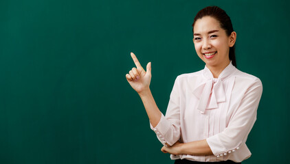 Portrait closeup shot of Asian young female beautiful school teacher tutor professor lecturer standing smiling crossed arm holding hand and finger pointing up in front of chalkboard in university