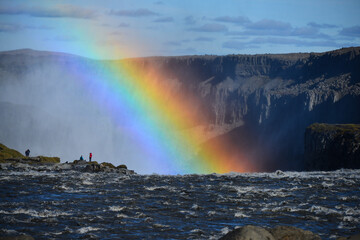 Hikers and a rainbow at the edge of Dettifoss waterfall, Jokulsargljufur canyon, Vatnajökull National Park, Iceland