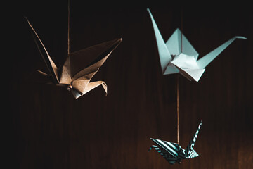 Three origami swans hanging from the roof with a wooden background
