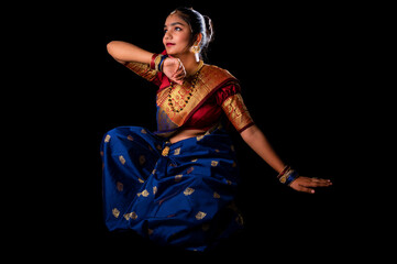 Fototapeta premium Beautiful Indian girl with clean healthy skin on black background. Wear red and blue Marathi saree.