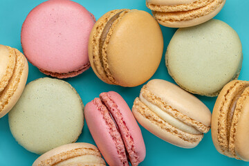 Background from multi-colored macaroons on a bright blue background, top view.