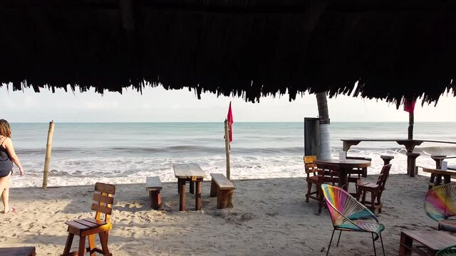 palomino la guajita en colombia, enfrente del mar, entre palmas y mucha arena con desayuno y olas que golpean  los pies. clima caluroso cielos despejados tomas con drone vuelo