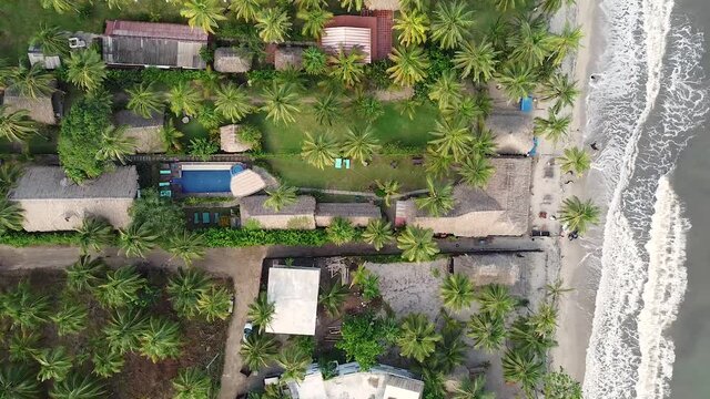 palomino la guajita en colombia, enfrente del mar, entre palmas y mucha arena con desayuno y olas que golpean  los pies. clima caluroso cielos despejados tomas con drone vuelo