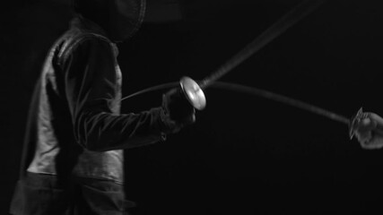 Man in white uniform fencing with opponent in black