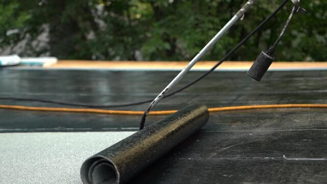Heating Roll Of Bitumen Roofing Felt With Gas Torch Flame. close up