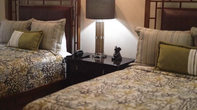 room with two beds next to bedside table and lighted lamp