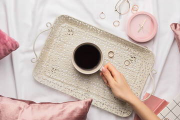 Woman with cup of coffee on bed