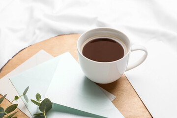 Board with cup of coffee and envelopes on bed