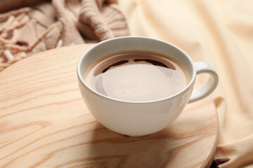 Wooden board with cup of coffee on bed, closeup