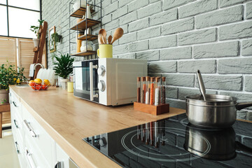 Modern microwave and spices on table in kitchen