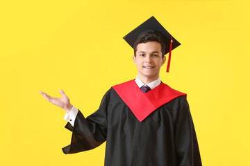 Male graduating student showing something on color background