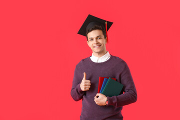 Male graduating student showing thumb-up on color background
