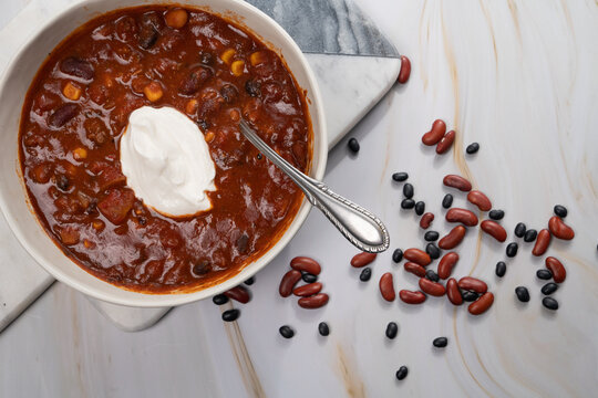 Chili stew with sour cream in a bowl with spoon