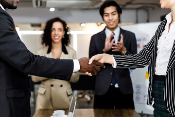 Selective focus and close up hands of African black businessman and caucasian white businesswoman with formal style doing successful handshake for congratulations and dealing agreement contract.